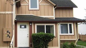 A two-story residential building with a beige exterior, a front door, and two windows. - Bk Guest house (Anacortes)
