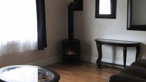 A living room with a round table, a sofa, a fireplace, and a window with curtains. - Bk Guest house (Anacortes)