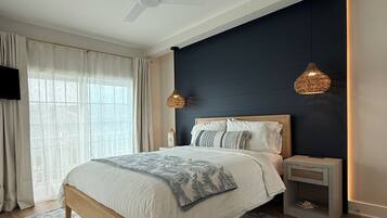 A modern bedroom with a bed, a ceiling fan, a nightstand, and a wall-mounted lamp.