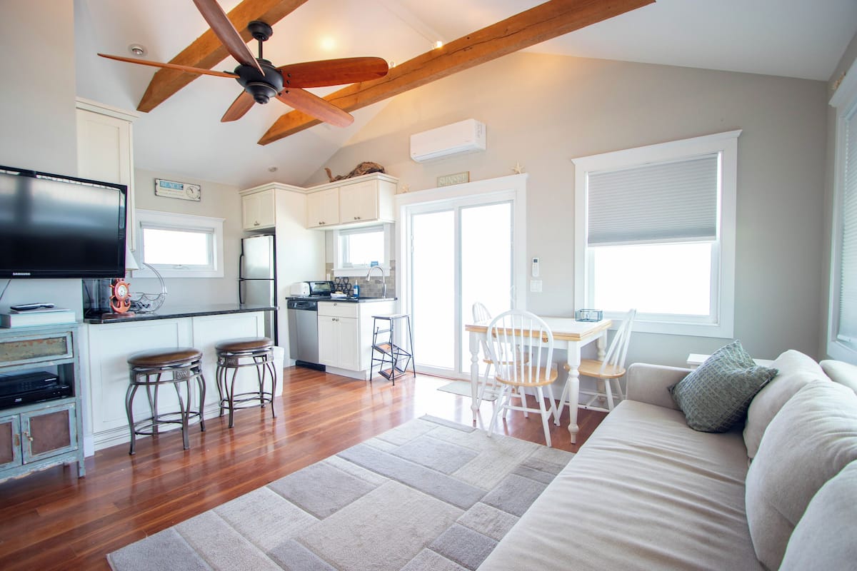 A spacious kitchen with wooden floors, a ceiling fan, and a dining area with a white table and chairs.