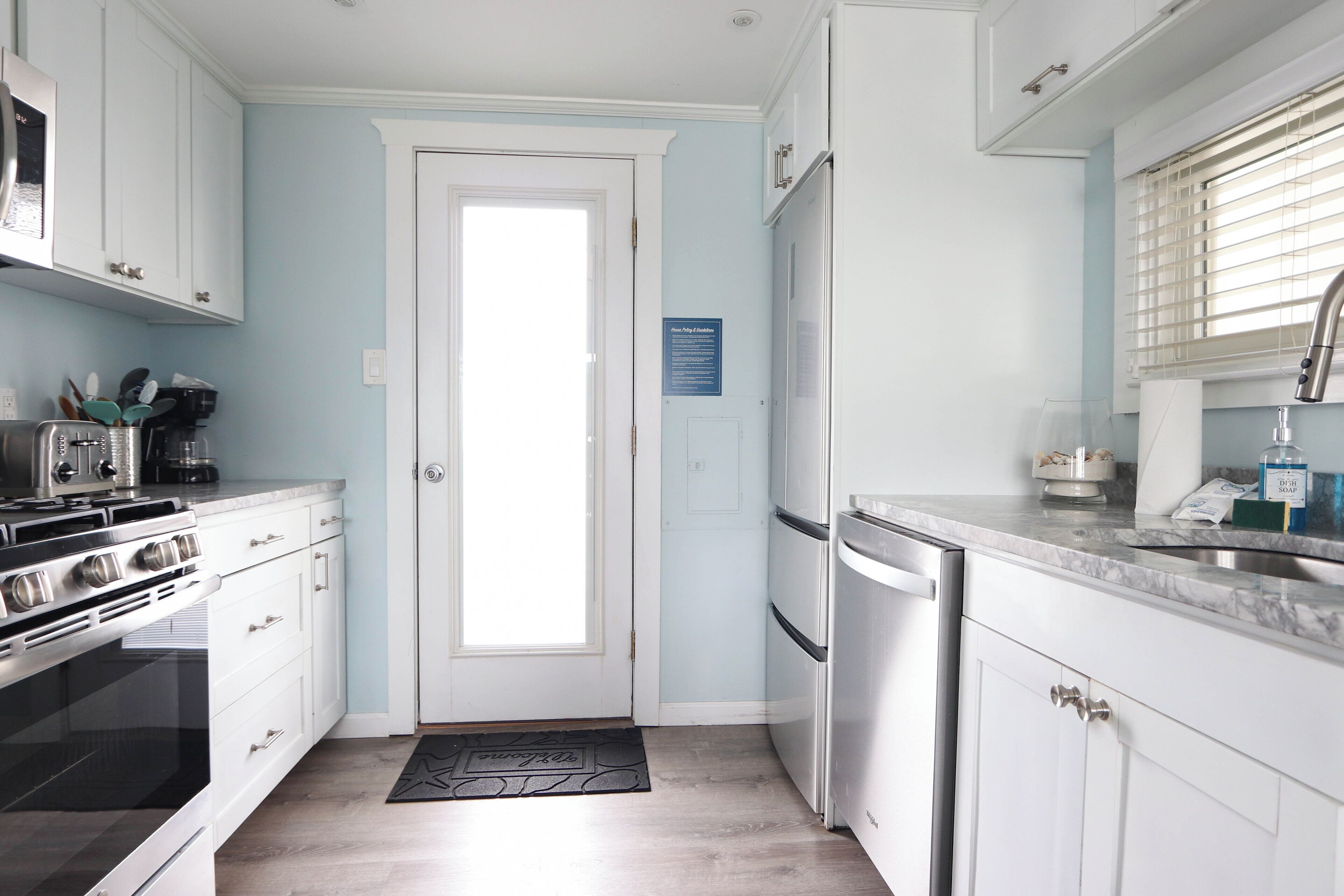 A modern kitchen with white cabinets, stainless steel appliances, and a black backsplash.