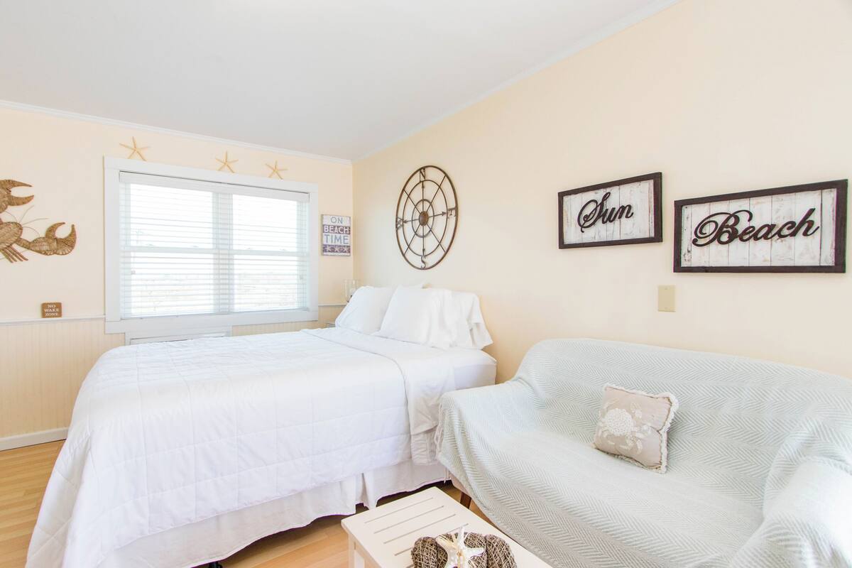 A bedroom with two beds, a window, wall decorations, and a sign reading 'ON BEACH TIME'.