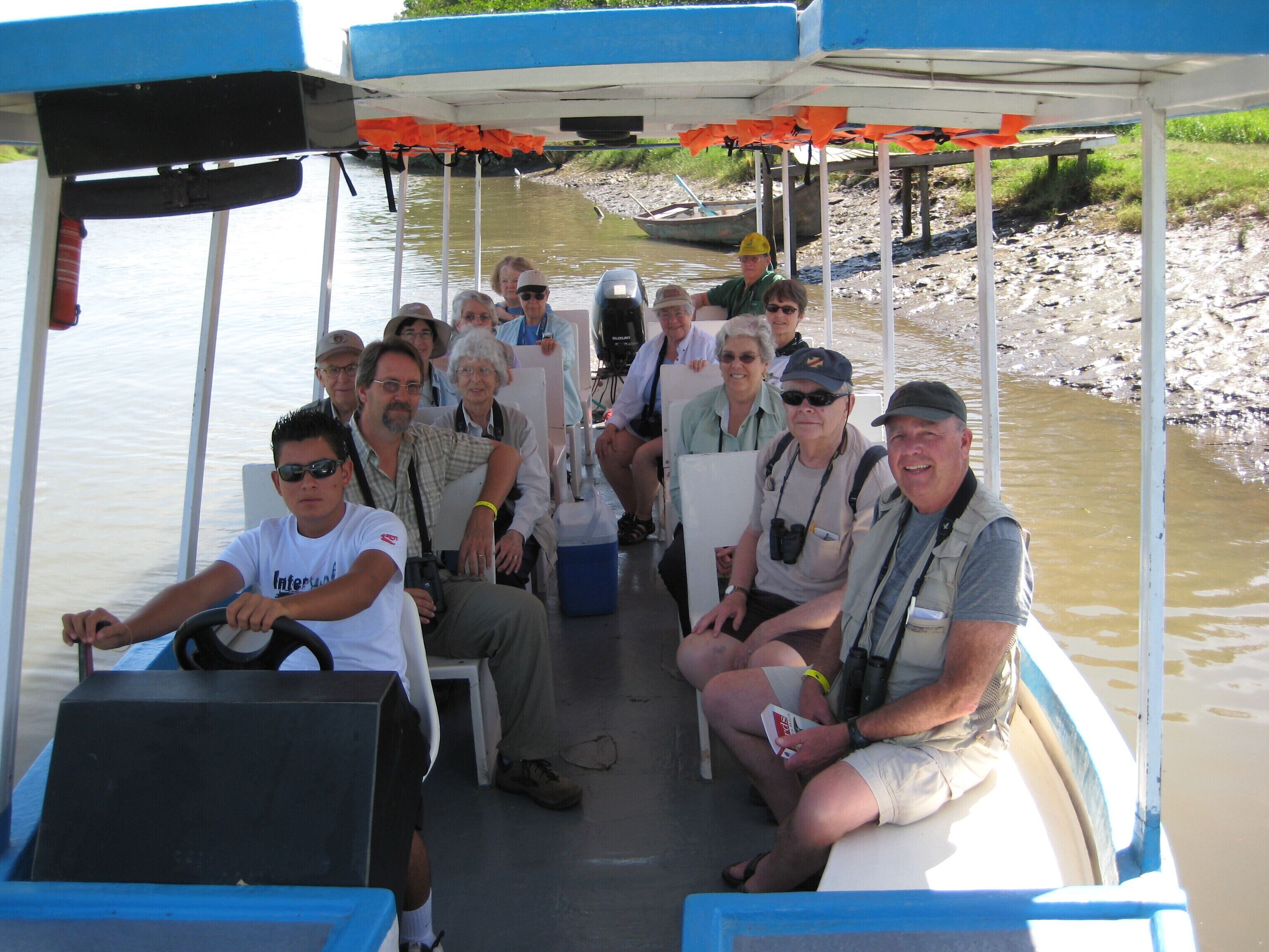 A boat with passengers, a steering wheel, and a blue and white color scheme.
