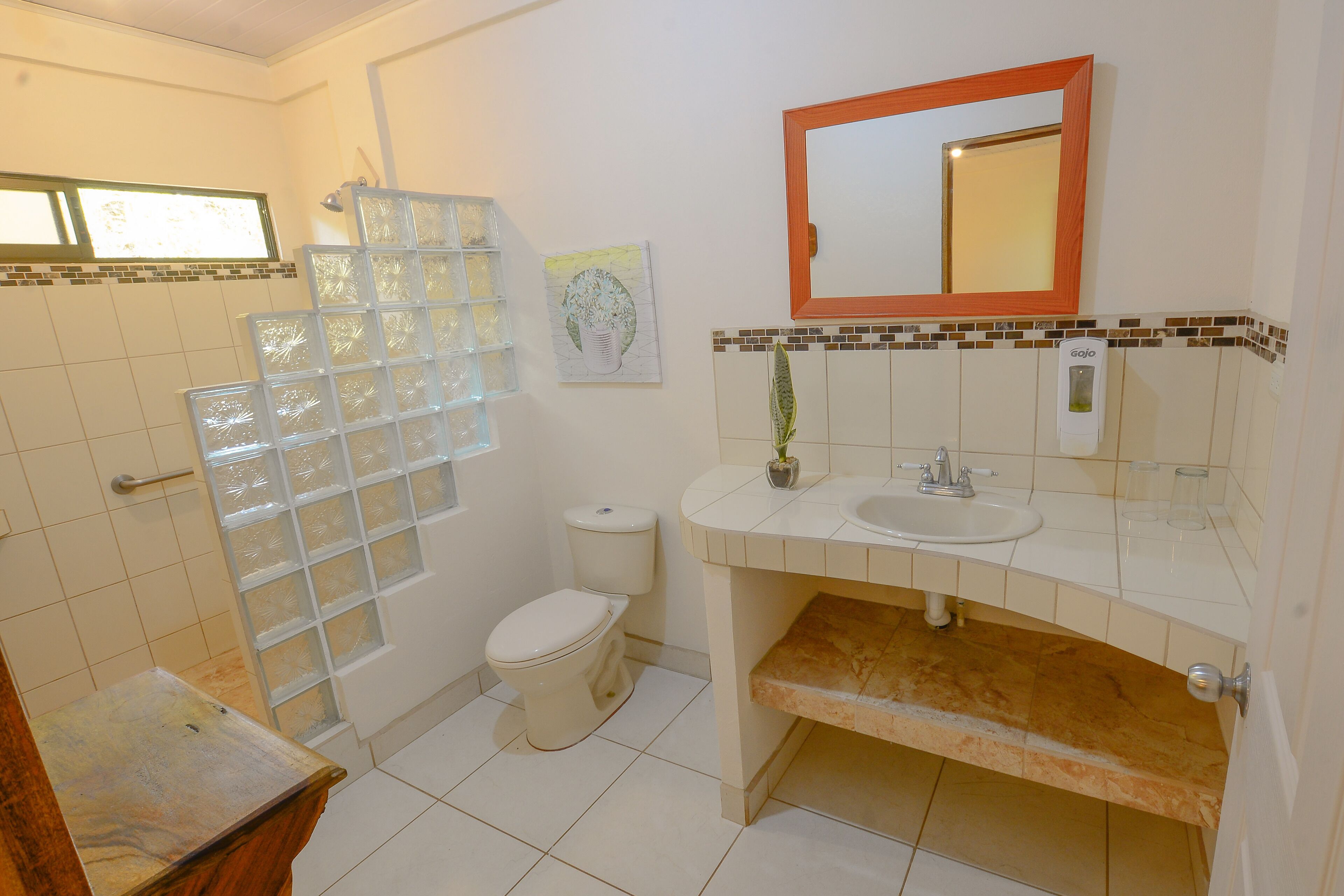 A bathroom with a toilet, sink, mirror, and glass shower enclosure.
