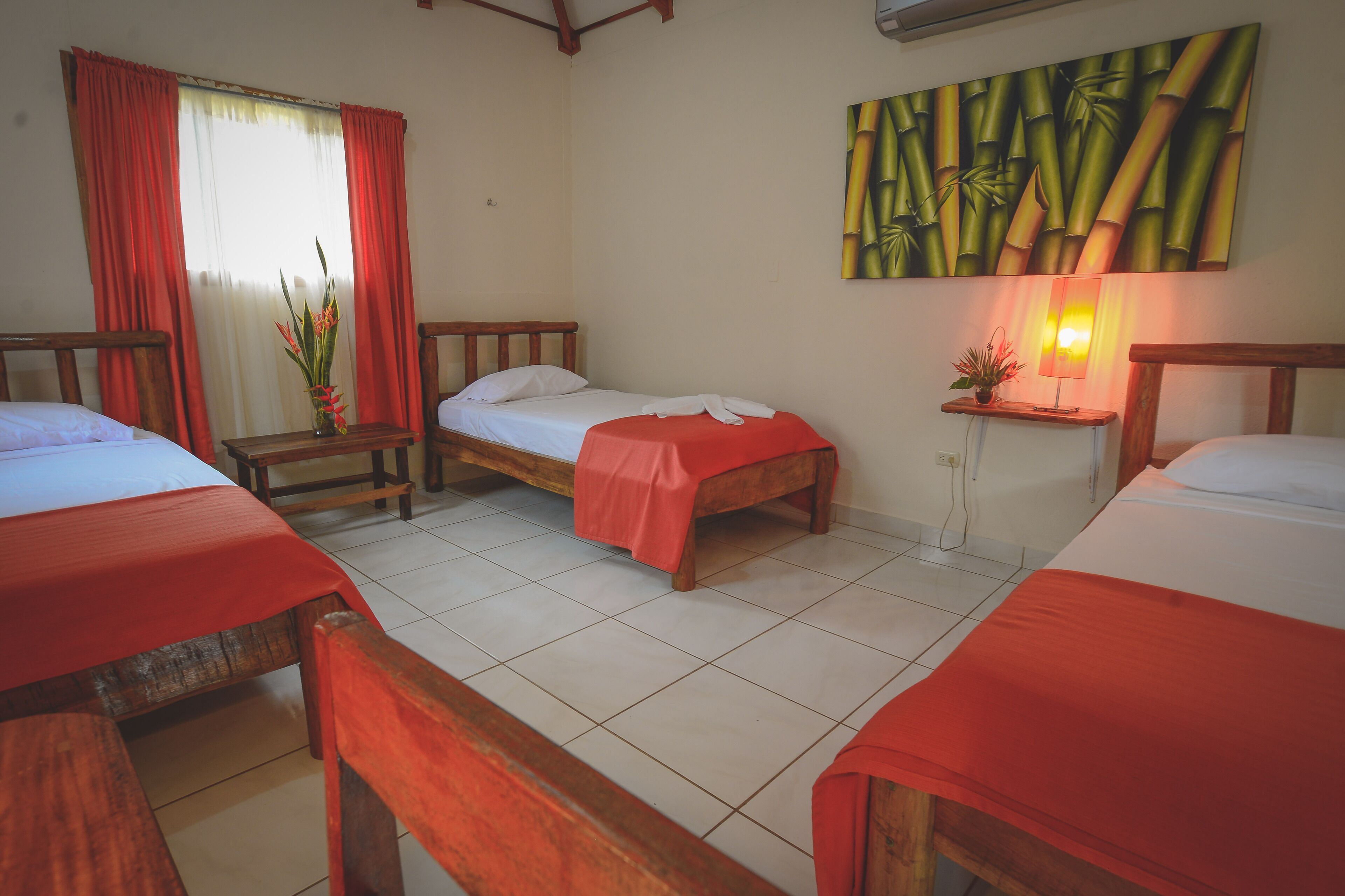 A hotel room with two single beds, a wooden headboard, a nightstand with a lamp, and a wall painting.