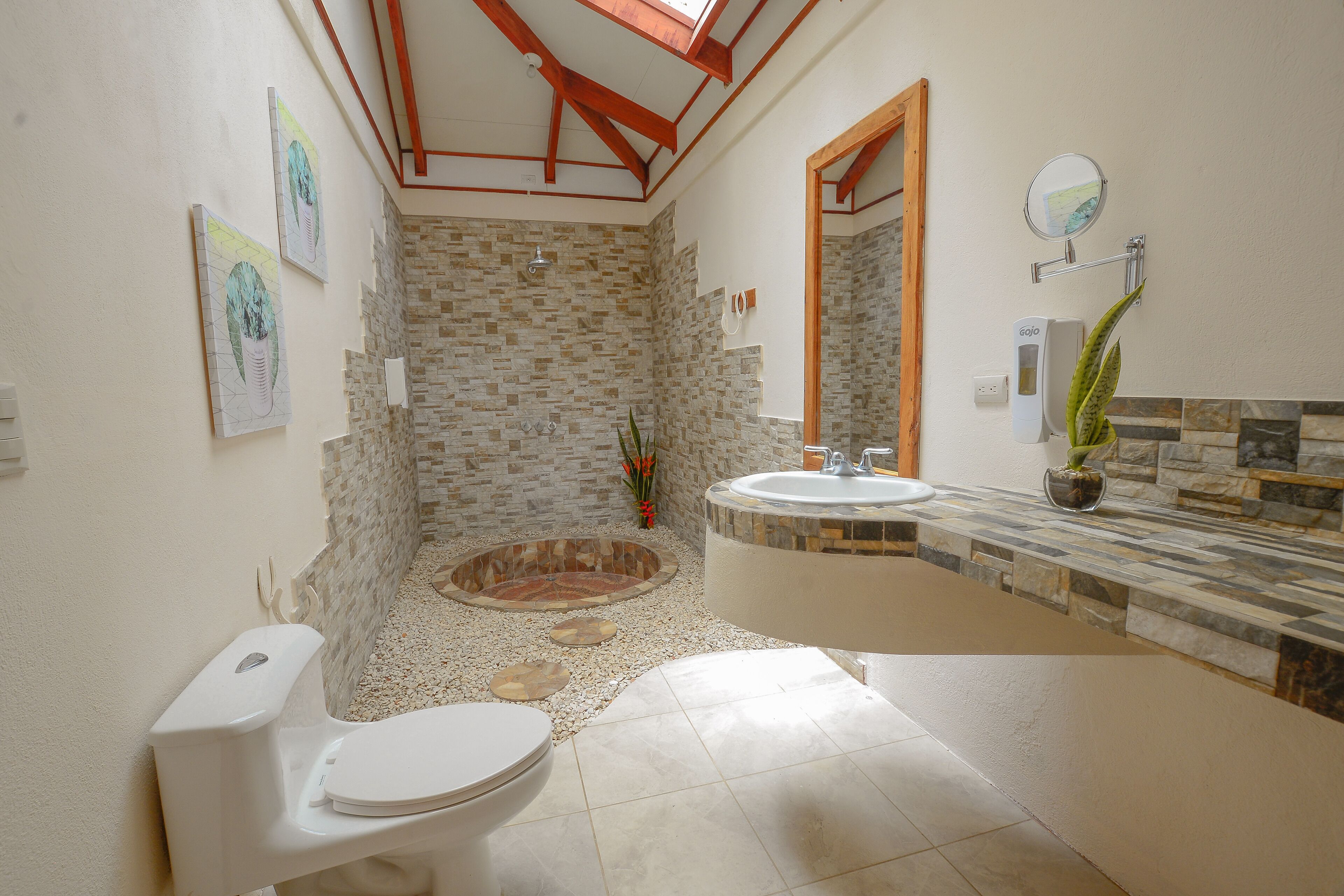 A bathroom with a stone wall, a bathtub, a toilet, and a sink.