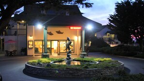 A hotel with a 'NO VACANCY' sign, a fountain, and a well-lit entrance. - Emerald Dolphin Inn & Mini Golf (Fort Bragg)