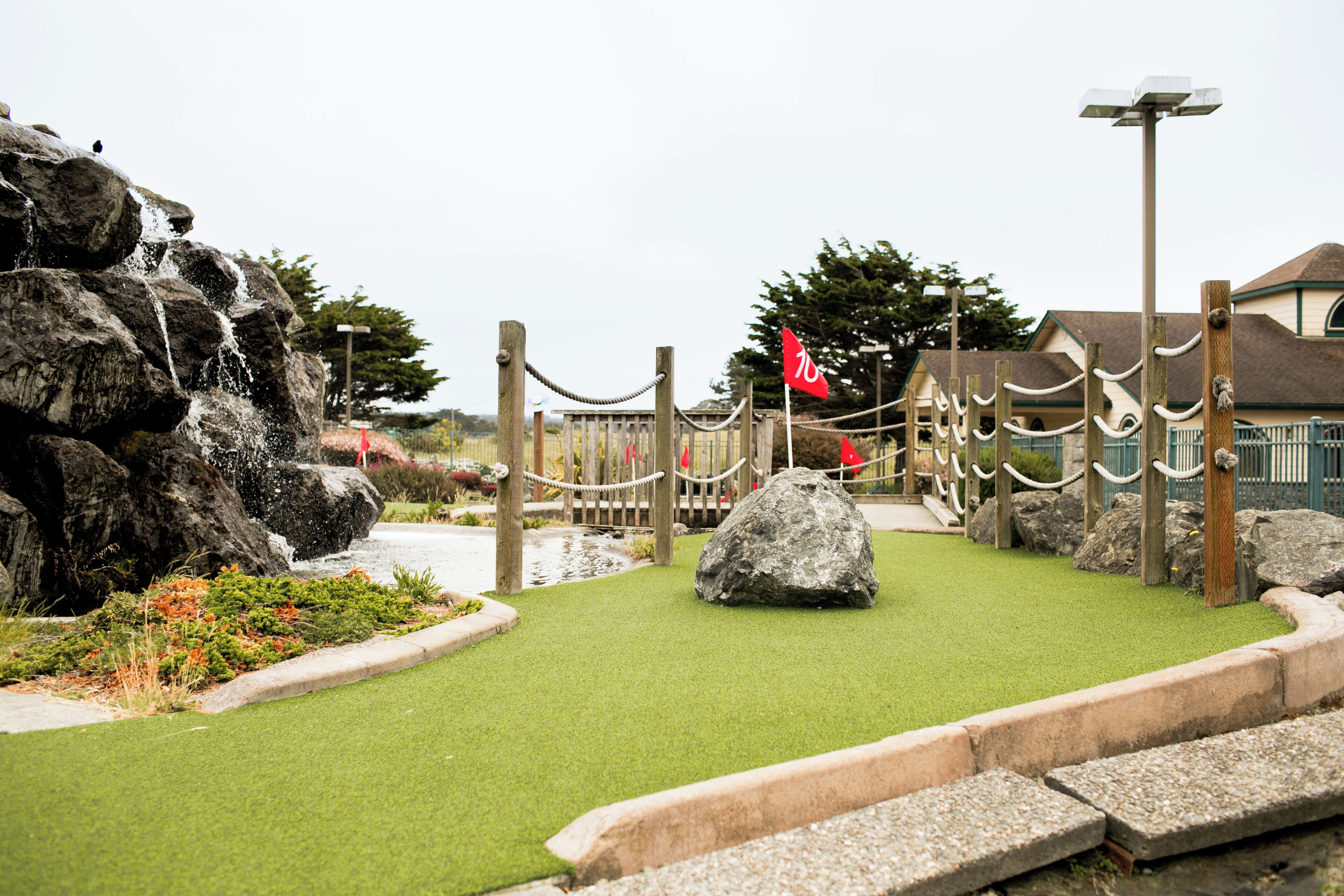 Un jardin de rocaille agrémenté d’un élément aquatique, d’une clôture en bois et d’un sentier.