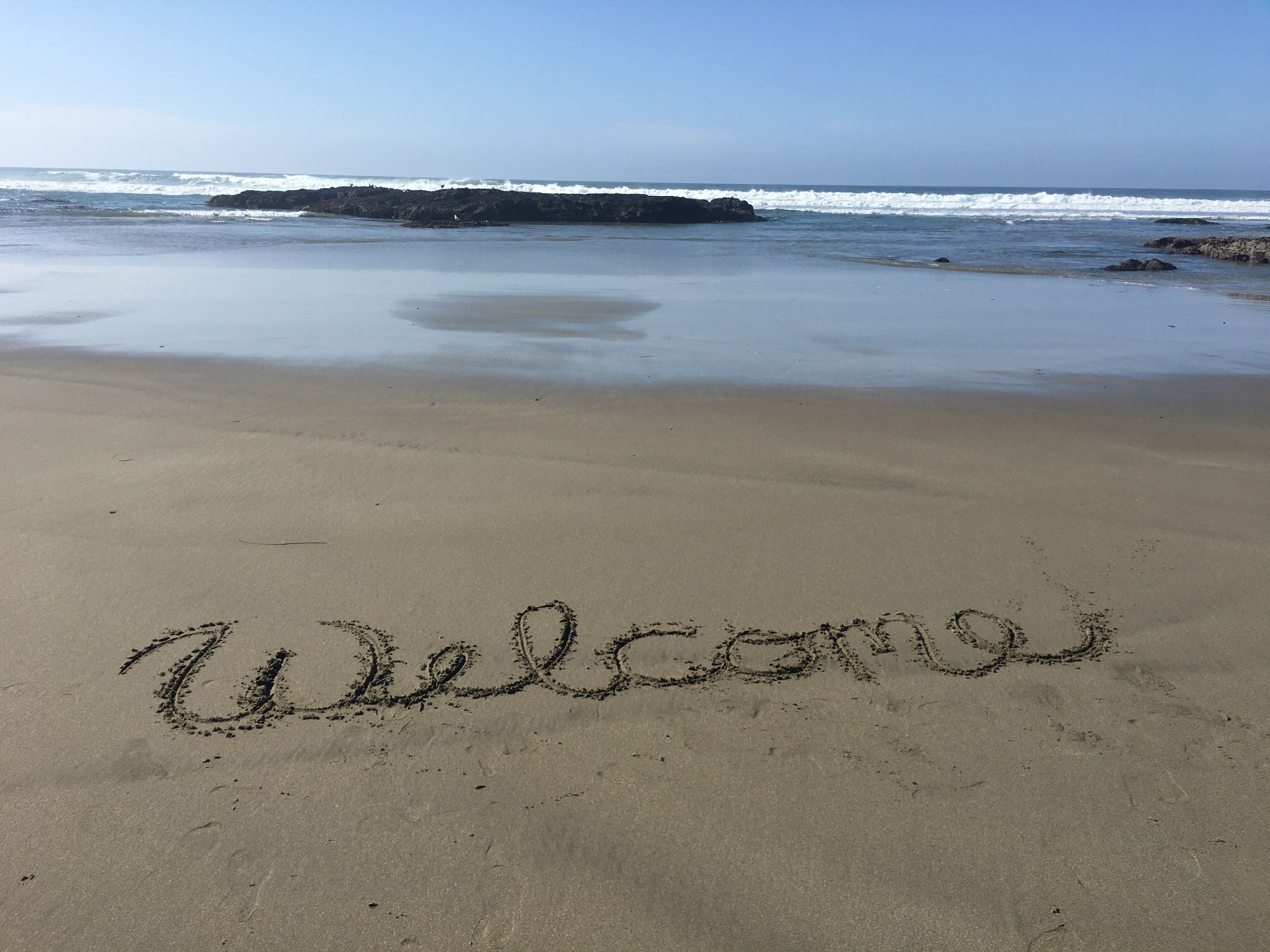 A beach with the word "Welcome" written in the sand.