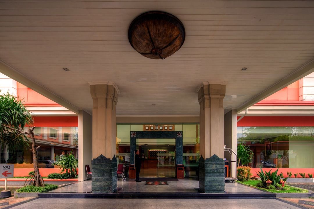 A hotel entrance with a central archway, columns, and a ceiling fan.