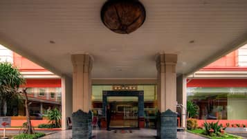 A hotel entrance with a central archway, columns, and a ceiling fan.