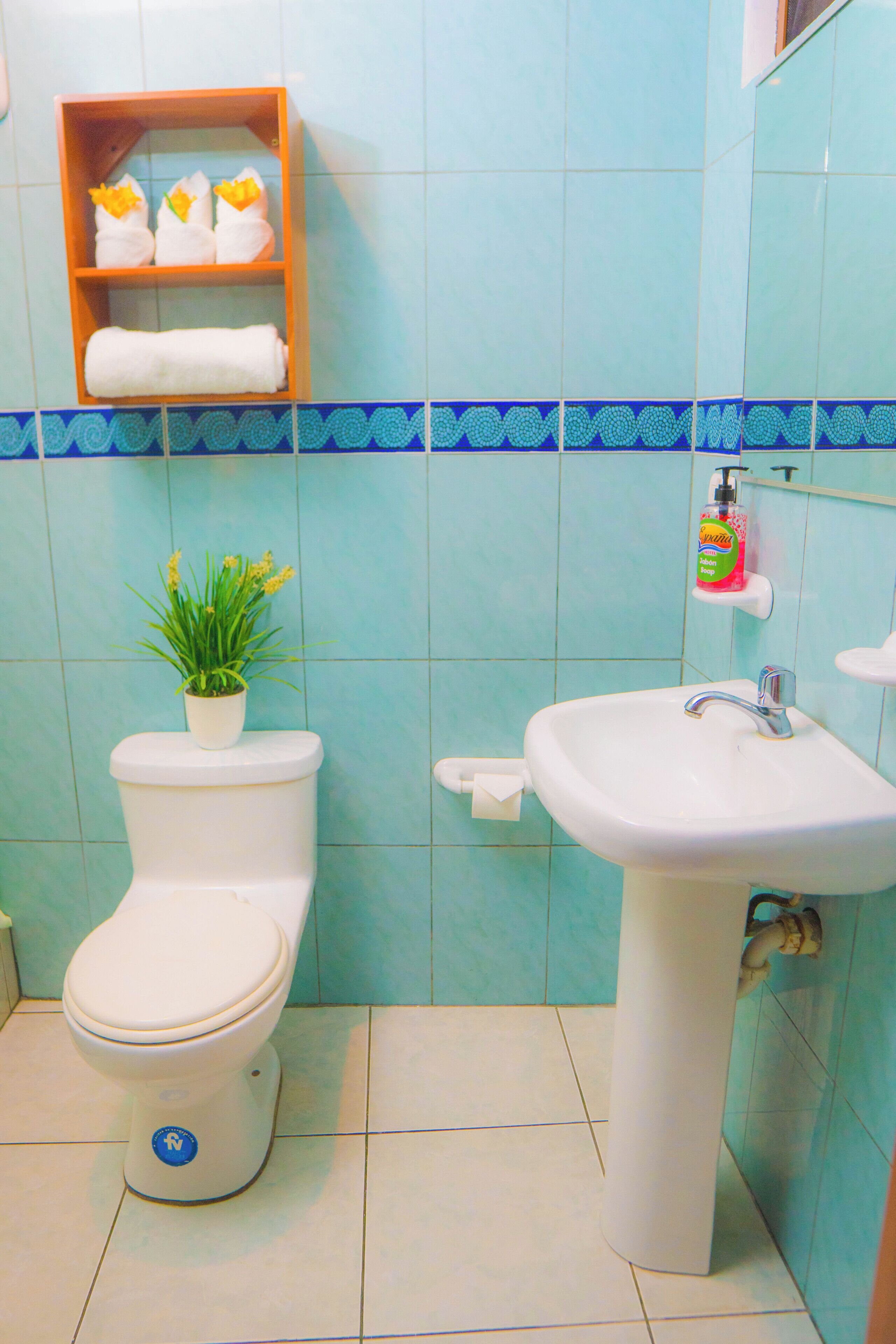 Une salle de bain avec des toilettes, un lavabo et une étagère avec des serviettes.