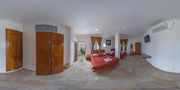 Habitación de hotel con una cama grande, un armario, televisión y un baño visible a través de una puerta abierta.