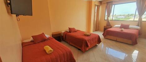 A hotel room with three beds, a flat-screen TV, and a large window with curtains.