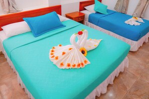 A hotel room with two beds, each with a blue bedspread and white pillows.