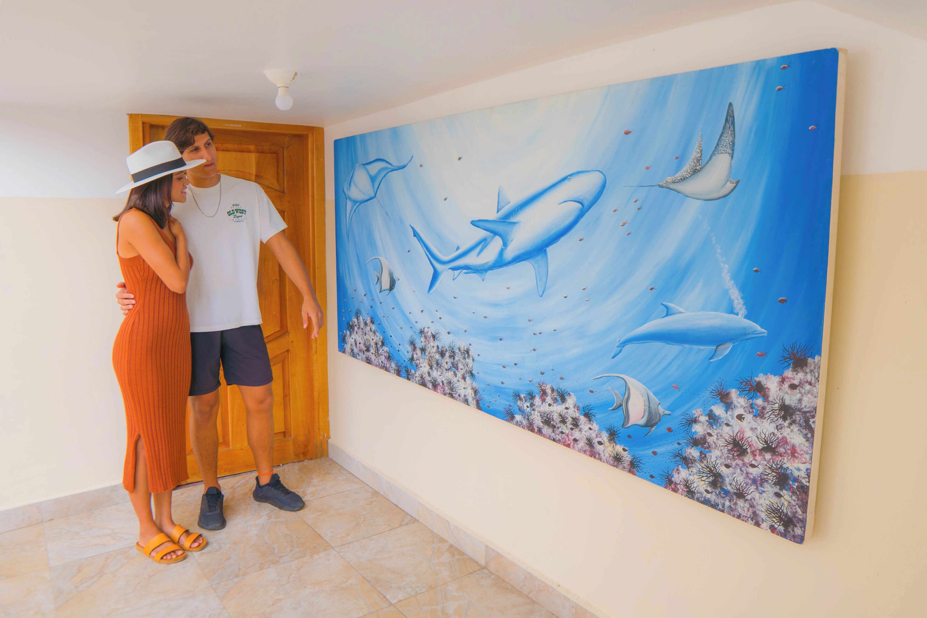 Ein Paar steht in einer Diele, an der Wand hängt ein großes Gemälde mit Meereslebewesen.