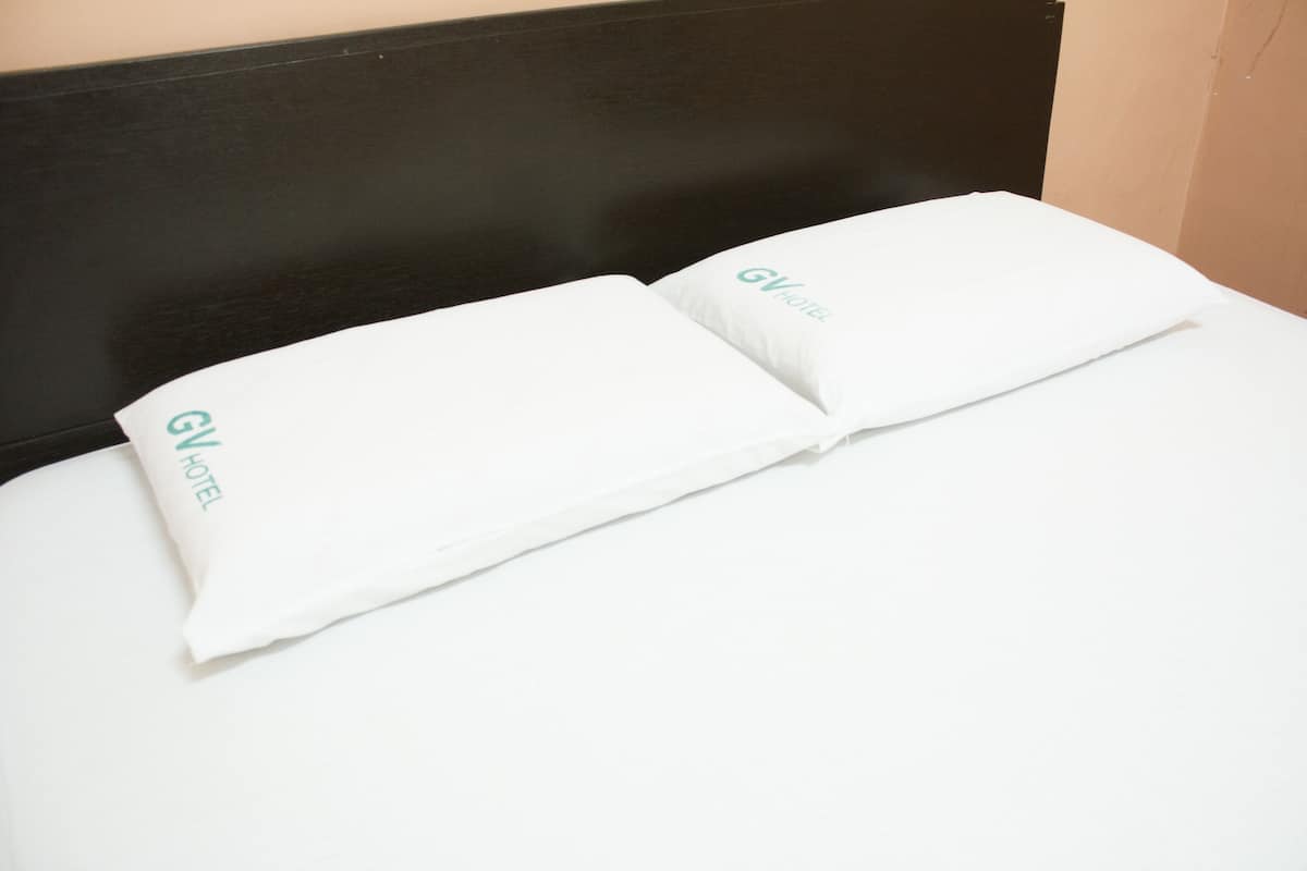 Un lit avec une tête de lit noire et un oreiller blanc portant l’inscription « GV Hotel ».