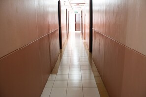 A long, narrow hallway with tiled floors and wooden walls, leading to an exit door at the end. - GV Hotel Naval (Naval)