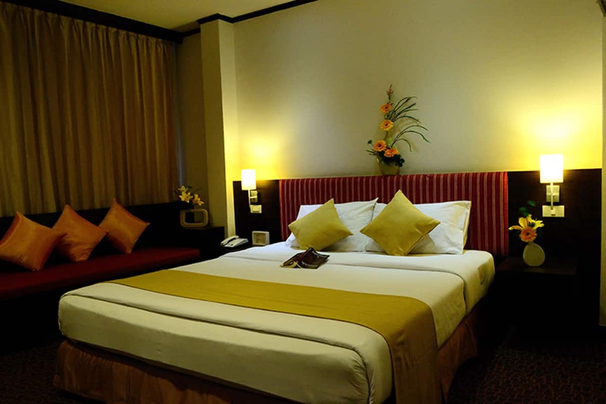 A hotel room with a large bed, a red sofa, and two bedside lamps.