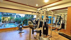 Un gimnasio con diversas máquinas de ejercicio, piscina y vistas al exterior.