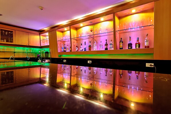 A bar area with shelves of liquor bottles and glasses, a polished reflective floor, and wooden cabinetry. - Bossotel Bangkok (Bangkok)