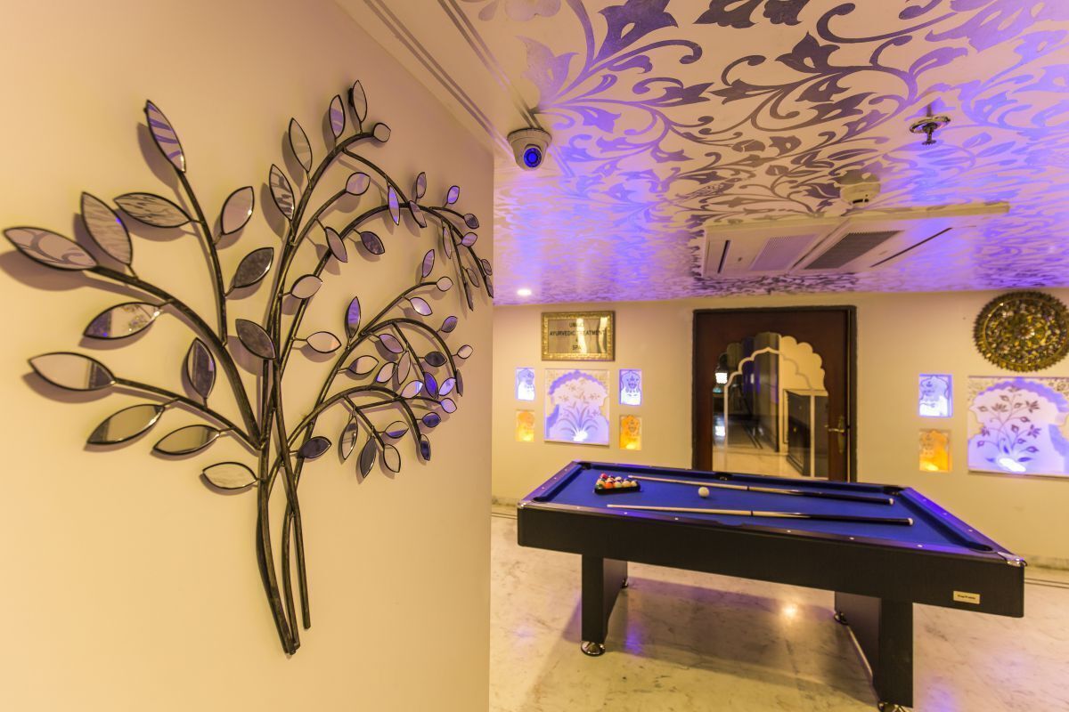 A billiards table in a room with a decorative wall art piece and a patterned ceiling.