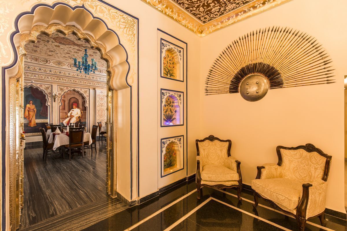 Una habitación con decoración elaborada, que incluye un espejo que refleja un comedor, obras de arte enmarcadas y un abanico decorativo.