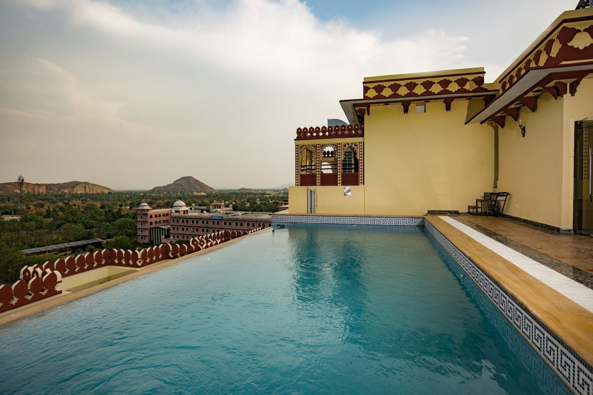 A swimming pool with a view of a hill and a building with traditional architecture.