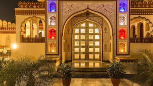 An ornate entrance with intricate carvings and a large central door, surrounded by potted plants.