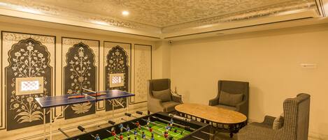 Una habitación con mesa de fútbolín, mesa de ping pong y dos sillones.