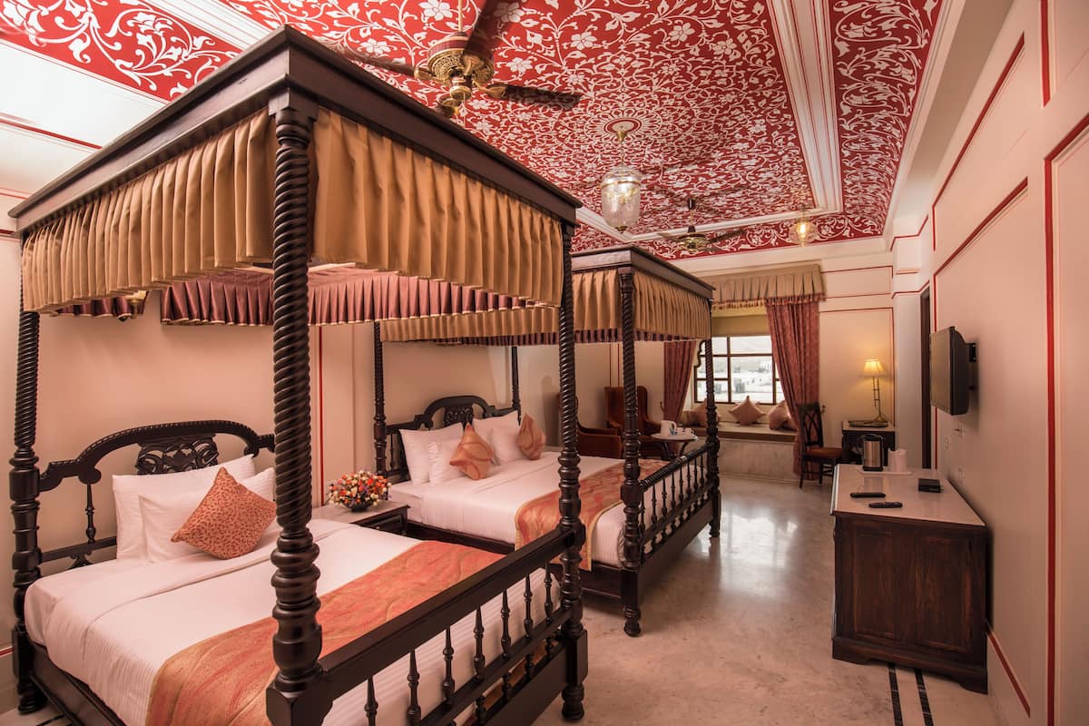 A four-poster bed with a canopy, two bedside tables, a nightstand, and a television on the wall.