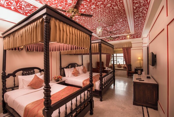 A four-poster bed with a canopy, two bedside tables, a nightstand, and a television on the wall.