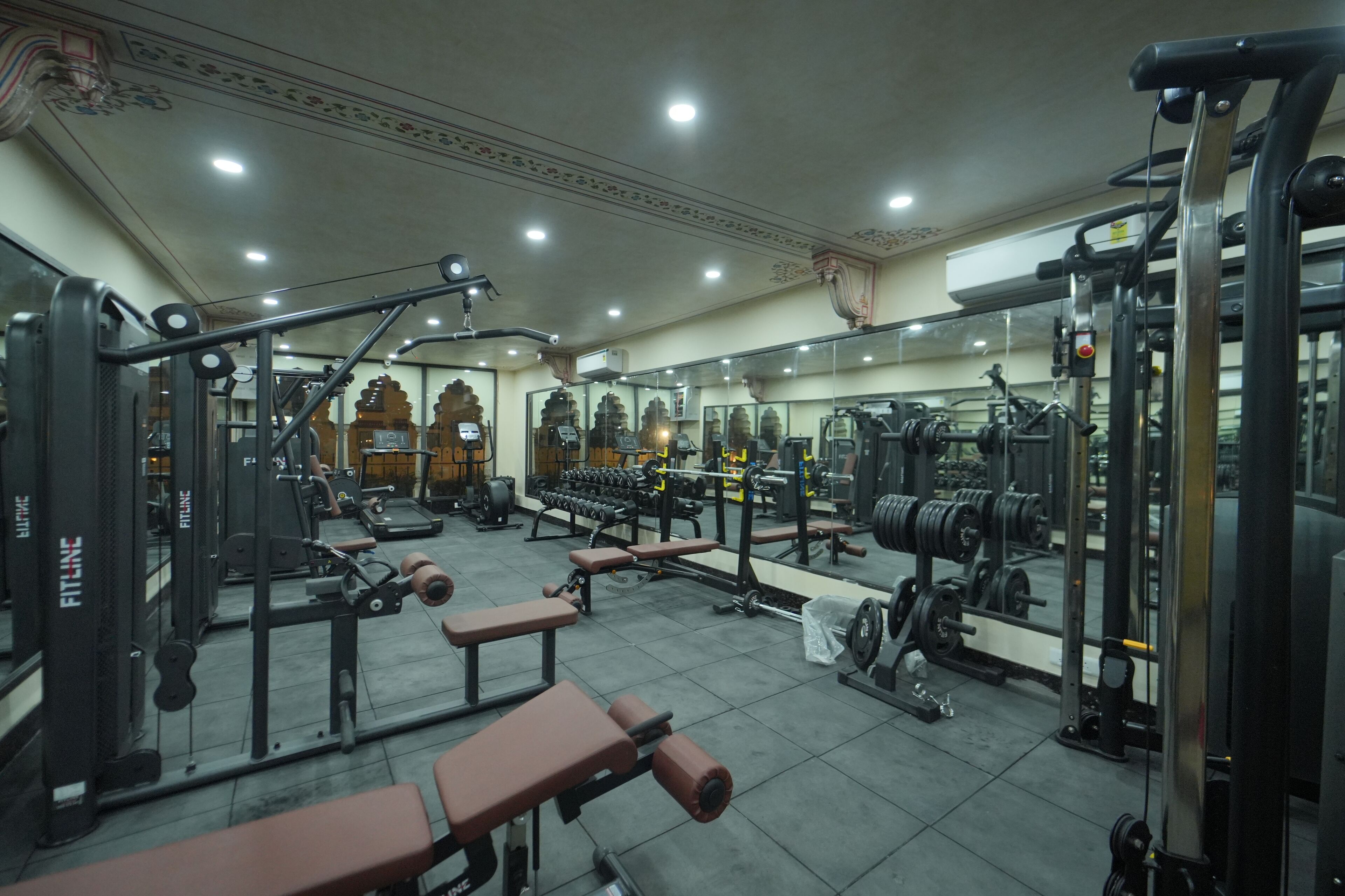 A gym with various exercise equipment, benches, and weight racks.