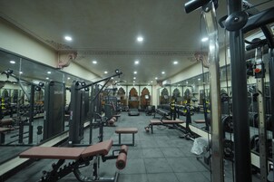 Un gimnasio con diversos equipos de ejercicio, bancos y espejos en las paredes.