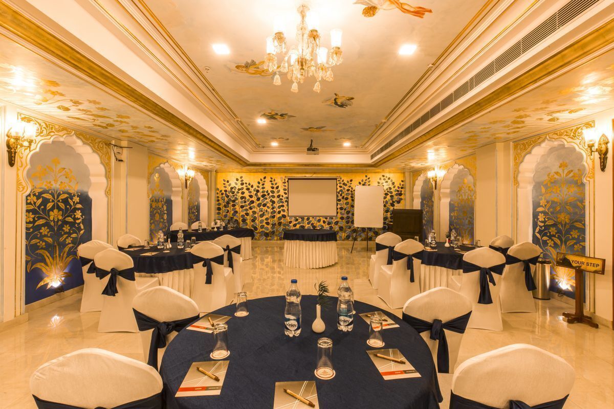 A conference room with round tables, white chairs, and a chandelier.