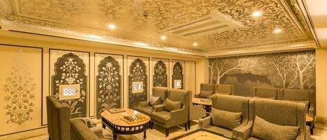 A room with a chessboard, sofas, and a decorative ceiling.