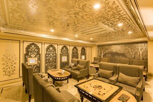 A room with a chessboard, sofas, and a decorative ceiling.