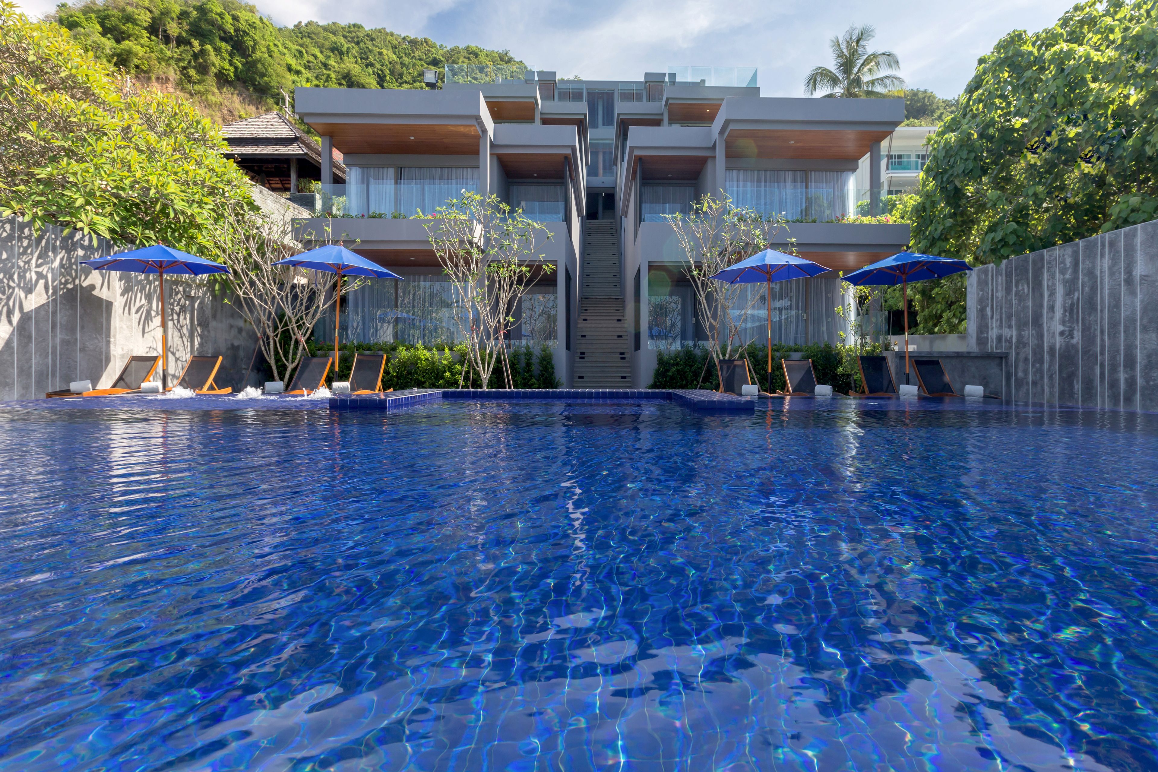 Un hôtel moderne doté d’une piscine, de plusieurs étages et de parasols installés à l’extérieur.