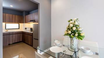 A modern kitchen with dark wood cabinets, a glass dining table with white plates, and a vase of white flowers.