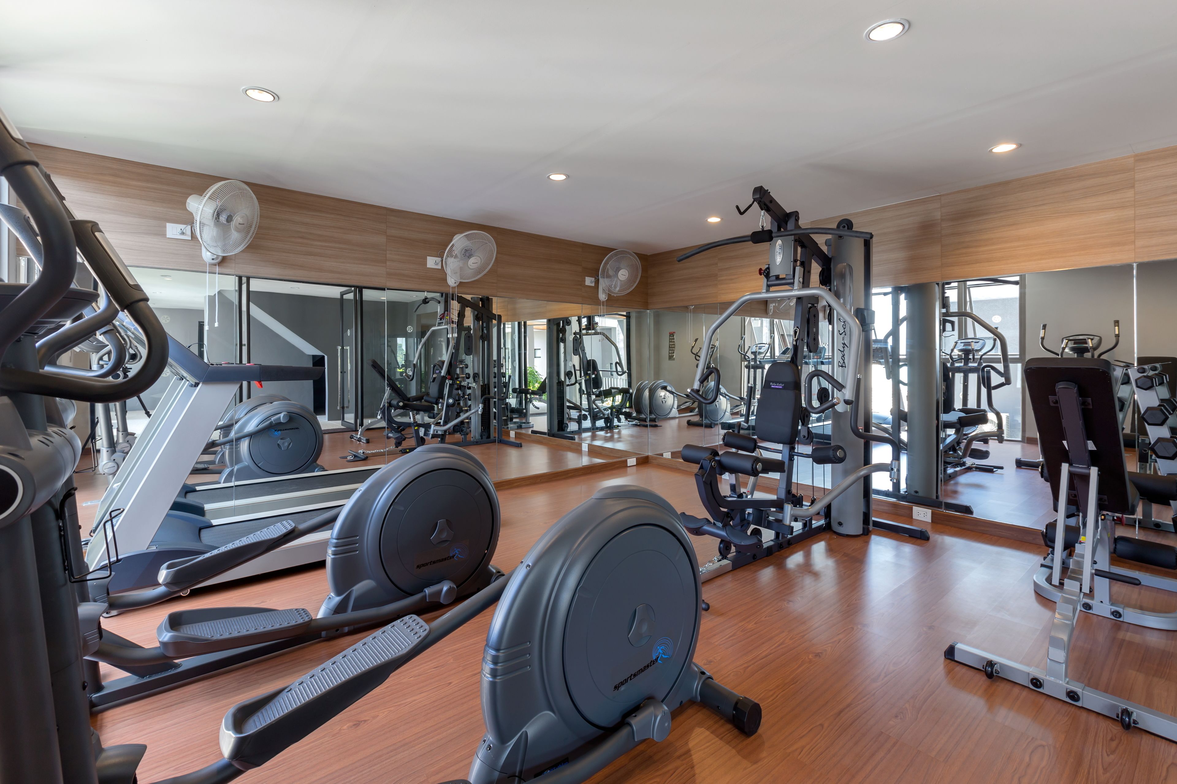 Un gimnasio con diversos equipos de ejercicio, incluyendo cintas de correr, bicicletas estáticas y máquinas de pesas.