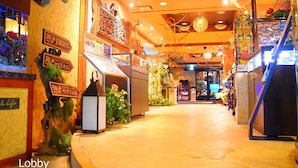 A lobby with a stone floor, wooden accents, and various signs indicating different levels.