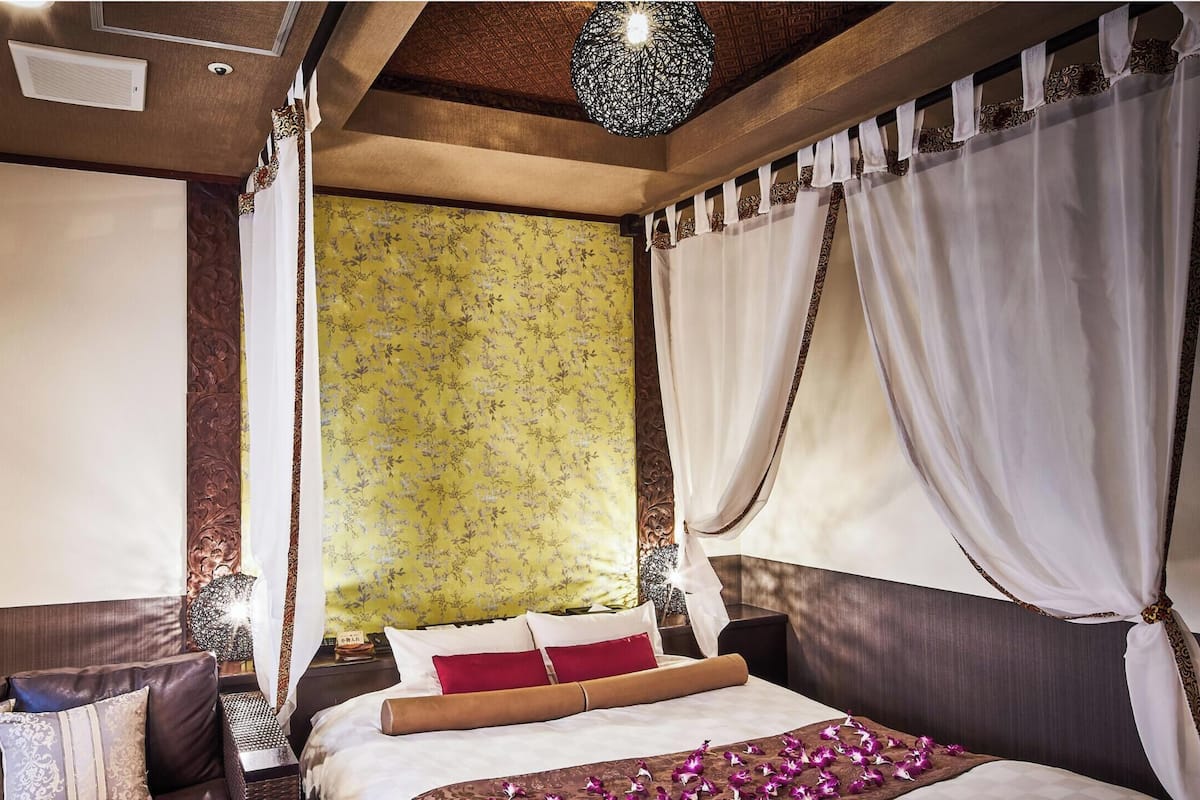 Ein Schlafzimmer mit einem Bett, einem Nachttisch, einer Lampe und Vorhängen.