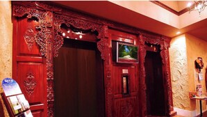 Una habitación con puertas de madera ornamentadas, un televisor y una pequeña mesa con objetos encima.