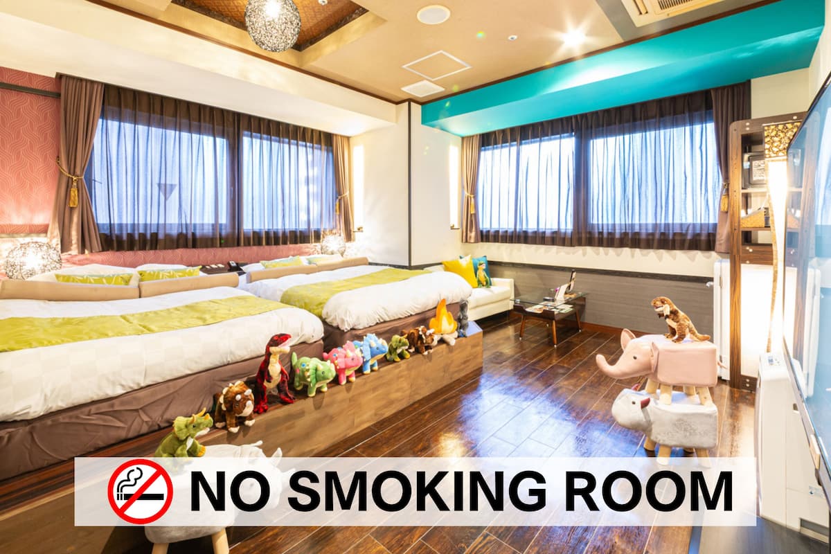 Ein Hotelzimmer mit Rauchverbot-Schild, einer Couch, einem Bett und einem Fenster mit Vorhängen.