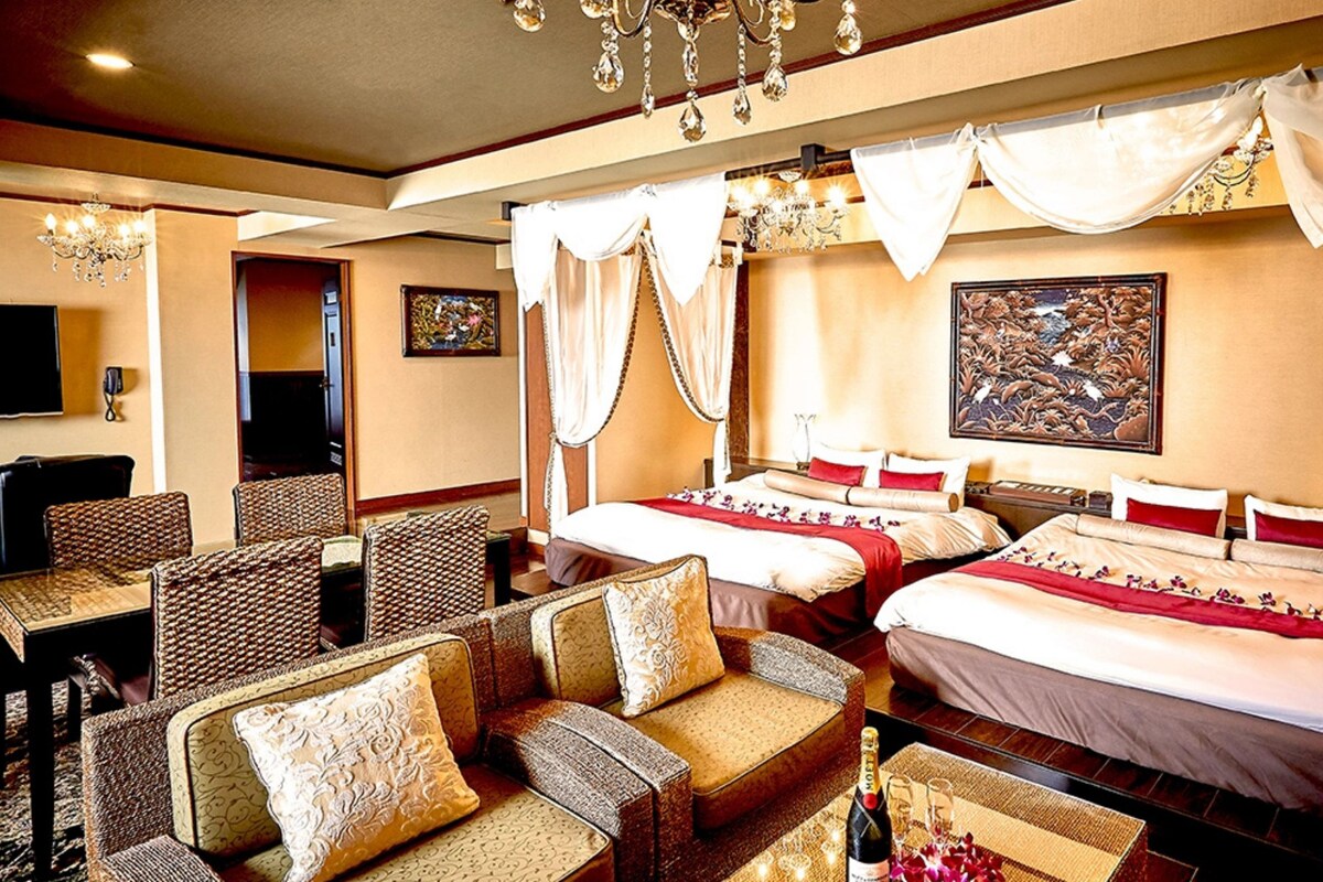 A hotel room with two beds, a sofa, and a television.