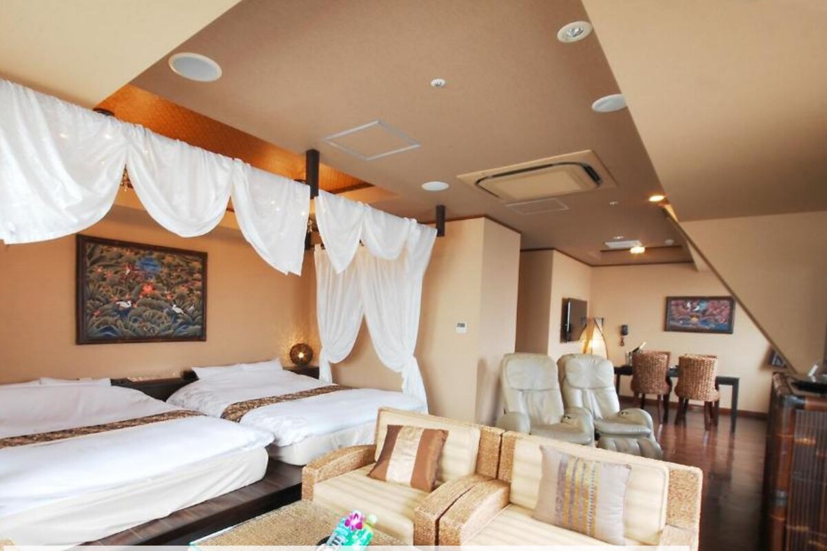 A hotel room with a bed, a sofa, and a dining area.