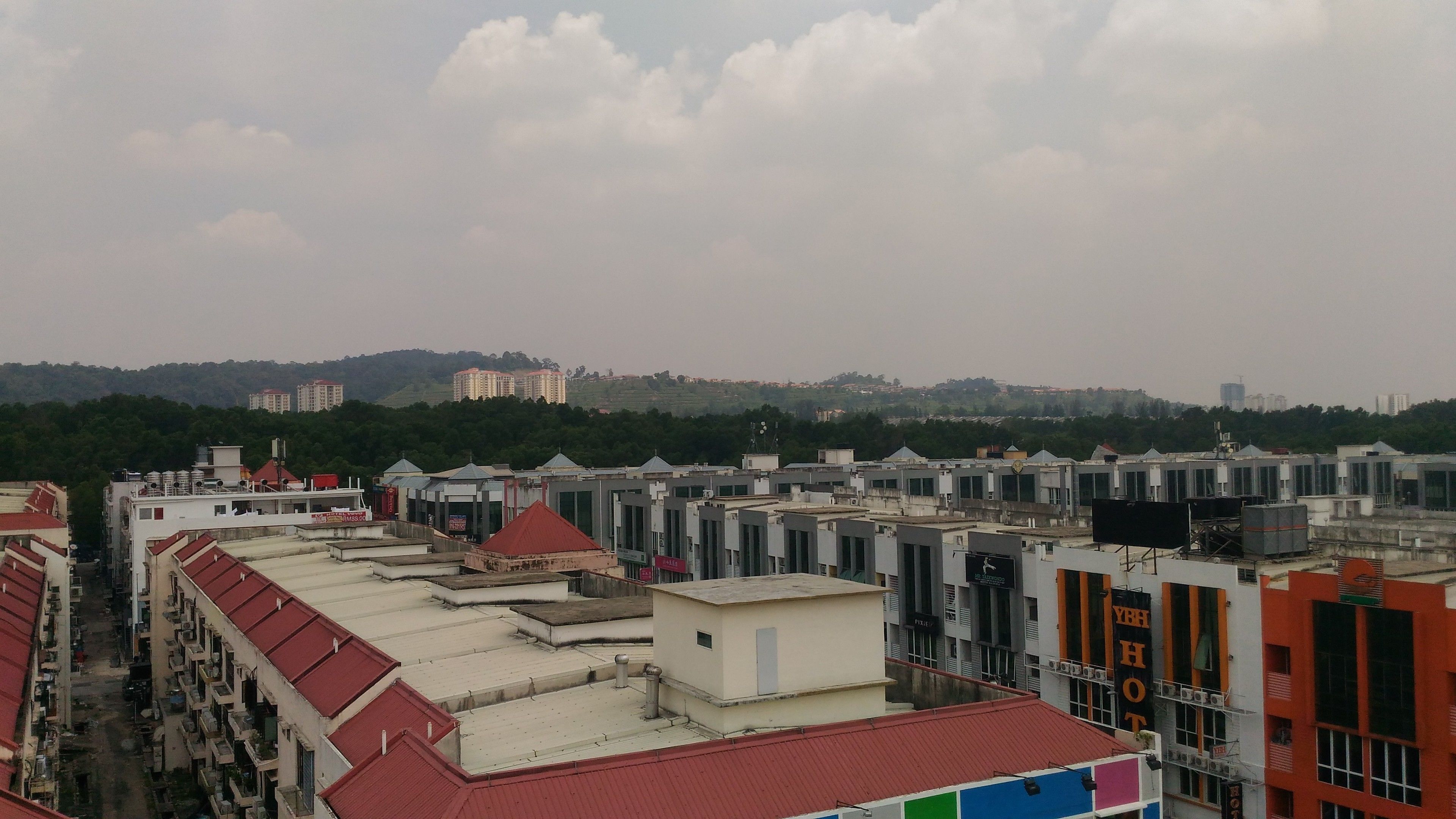 A row of buildings with flat roofs and a distant view of a hilly landscape.