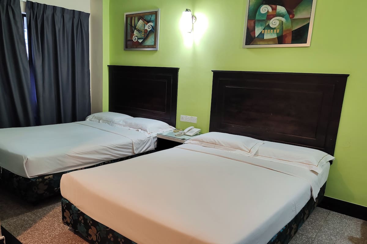 Two single beds with dark wooden headboards, a telephone on the wall, and abstract art on the green walls.