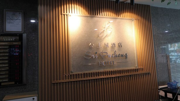 Un mostrador de recepción de hotel con diseño de paneles de madera y un cartel que dice "Sichuang Hotel".