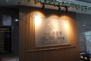 A hotel reception desk with a wooden panel design and a sign that reads "Sichuang Hotel".
